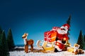 Christmas scene with Santa Claus tied to Xmas tree with reindeers, pine forest and snow on blue night sky background Royalty Free Stock Photo