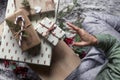 Christmas scene - tower of gifts with eco paper, person sitting on the carpet reaching the gifts