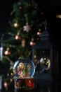 Christmas scene with tree, lights and snow globe. Selective focus on black background Royalty Free Stock Photo