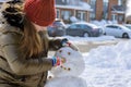 Christmas season happy child girl playing with a snowman on snowy winter a teenage girl sculpts snowman