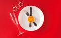 Christmas served dinner, meal table design on red background. White plate, champagne glass, star, dried orange, fork, knife. New