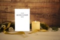 Christmas setting for a book presentation: book with blank cover settled with three lit candles , white organza and gold satin Royalty Free Stock Photo