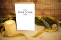 Christmas setting for a book presentation: book with blank cover settled with three lit candles , white organza and gold satin Royalty Free Stock Photo