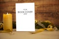 Christmas setting for a book presentation: book with blank cover settled with three lit candles , white organza and gold satin Royalty Free Stock Photo