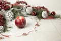 Christmas setting: a red lit candle with cross screen effect on foreground surrounded by pine branches, red baubles, red and white Royalty Free Stock Photo