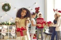 African-American girl holding out hands with Christmas present, looking at camera and smiling