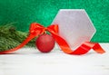Christmas shiny New Year`s ball with bow and twisted ribbon with fir branches. Behind green blurred with sparkle background Royalty Free Stock Photo