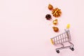 Christmas shopping cart with balls, holiday decorations and golden star confetti on pink pastel background top view. Flat lay Royalty Free Stock Photo