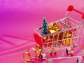 Christmas shopping cart with gift, holiday decorations on pink pastel background top view. Flat lay style. Christmas Royalty Free Stock Photo