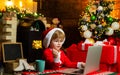 Christmas shopping concept. Gifts service. Little genius. Santa little helper. Boy child with laptop near christmas tree