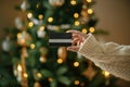 Christmas shopping online and black friday sales. Hand in cozy sweater holding credit card close up on background of christmas Royalty Free Stock Photo
