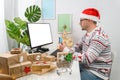 Christmas shopping online. The man wearing a sweater shopping online and using a credit card at the home office. Royalty Free Stock Photo