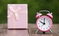 Christmas shopping, time to gift. Pink alarm clock and gift box Royalty Free Stock Photo
