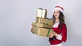 Christmas shopping woman holding many Christmas gifts in her arms wearing santa hat. Beautiful young female model on grey Royalty Free Stock Photo