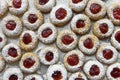 Christmas shortbread thumbprint cookies with strawberry jam powdered with castor sugar on white parchment paper on baking tray