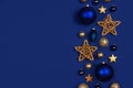 Christmas side border of dark blue and gold ornaments, top view on a blue background