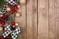 Christmas side border with white and black checked buffalo plaid ribbon, decorations and branches, overhead on a rustic wood backg Royalty Free Stock Photo