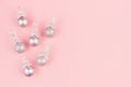 Christmas silver decorations - balls with glitter ribbons as decorative border on soft light pastel pink background, top view. Royalty Free Stock Photo