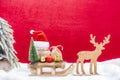 A christmas sled with presents, santa hat, fir tree and reindeer in the snow