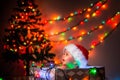 Christmas. A smiling happy baby in a Christmas hat sitting in a gift box. A garland lights up in the background. The Royalty Free Stock Photo