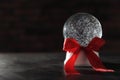 Christmas snow globe with red bow on dark. Space for text Royalty Free Stock Photo