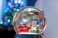 A Christmas snow globe with a snowman and christmasy ornaments