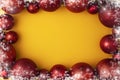 Christmas snowflake frame border with red balls or toy baubles on yellow pastel background. Flat lay, top view Royalty Free Stock Photo