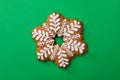 Christmas snowflake shaped gingerbread cookie on green background, top view