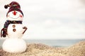 Christmas snowman in red santa hat and sunglasses at sunny beach. Holiday concept for New Years Cards. Royalty Free Stock Photo