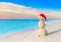 Christmas Snowman in red Santa hat at sunset sea beach Royalty Free Stock Photo