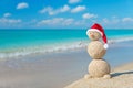 Christmas snowman in santa hat at tropical ocean beach