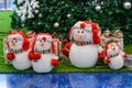 Christmas snowmen are sitting under a Christmas tree with gifts in red caps ear flaps with a star, mittens and colorful scarves Royalty Free Stock Photo