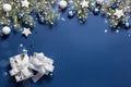 Christmas snowy border of gift box, shiny balls and stars, evergreen branches on blue background. New Year card Royalty Free Stock Photo