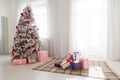 Christmas snowy Christmas tree with presents in a white room in winter Royalty Free Stock Photo