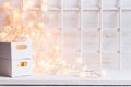 Christmas soft home decor with lights burning and boxes on a white wooden background. Royalty Free Stock Photo