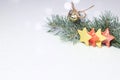 Christmas spruce branch, bells and yellow and red stars, sprinkled with artificial snow on a light background. Contains copy space Royalty Free Stock Photo