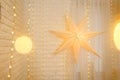 Christmas star on golden lights background on wall in living room. Large paper star glows against the backdrop of New