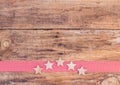 Christmas stars on red ribbon border and rustic wooden background Royalty Free Stock Photo