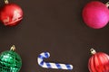 Christmas stick, red, wavy, pink and green ribbed ball on dark wooden table