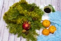 Christmas still life. branches of a green tree with decorations, would a Cup of coffee,three tangerine, and turquoise fabric on a