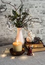 Christmas still life. Burning candle,stack of books, christmas tree, garland on the table Royalty Free Stock Photo