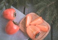 Christmas still life with fresh persimmon with fir-tree on wooden background. Top view. Royalty Free Stock Photo