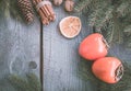 Christmas still life with fresh persimmon and cinnamon with fir-tree on wooden background. Top view. Royalty Free Stock Photo