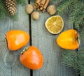 Christmas still life with fresh persimmon and cinnamon with pine tree on wooden background. Royalty Free Stock Photo