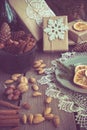 Christmas still life with giftbox, bowl with walnuts, almond, cinnamon, snowflakes on wooden table. Top view.