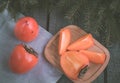 Christmas still life with persimmon with fir-tree on wooden background. Top view. Royalty Free Stock Photo