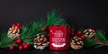 Christmas still life with red candle and fir branches with pine cones and holly berries on a dark background. Holiday card with Royalty Free Stock Photo