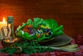 Christmas still life with salad of tomato, cheese, green onions and tricolor violet flowers, a candle, wooden spoons, a branch