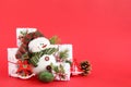 Christmas still life with snowman and gift boxes on a red background, decorated fir branches, pine cone and wooden decorations. Royalty Free Stock Photo