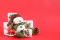 Christmas still life with snowman and gift boxes on a red background, decorated fir branches, pine cone and wooden decorations. Royalty Free Stock Photo